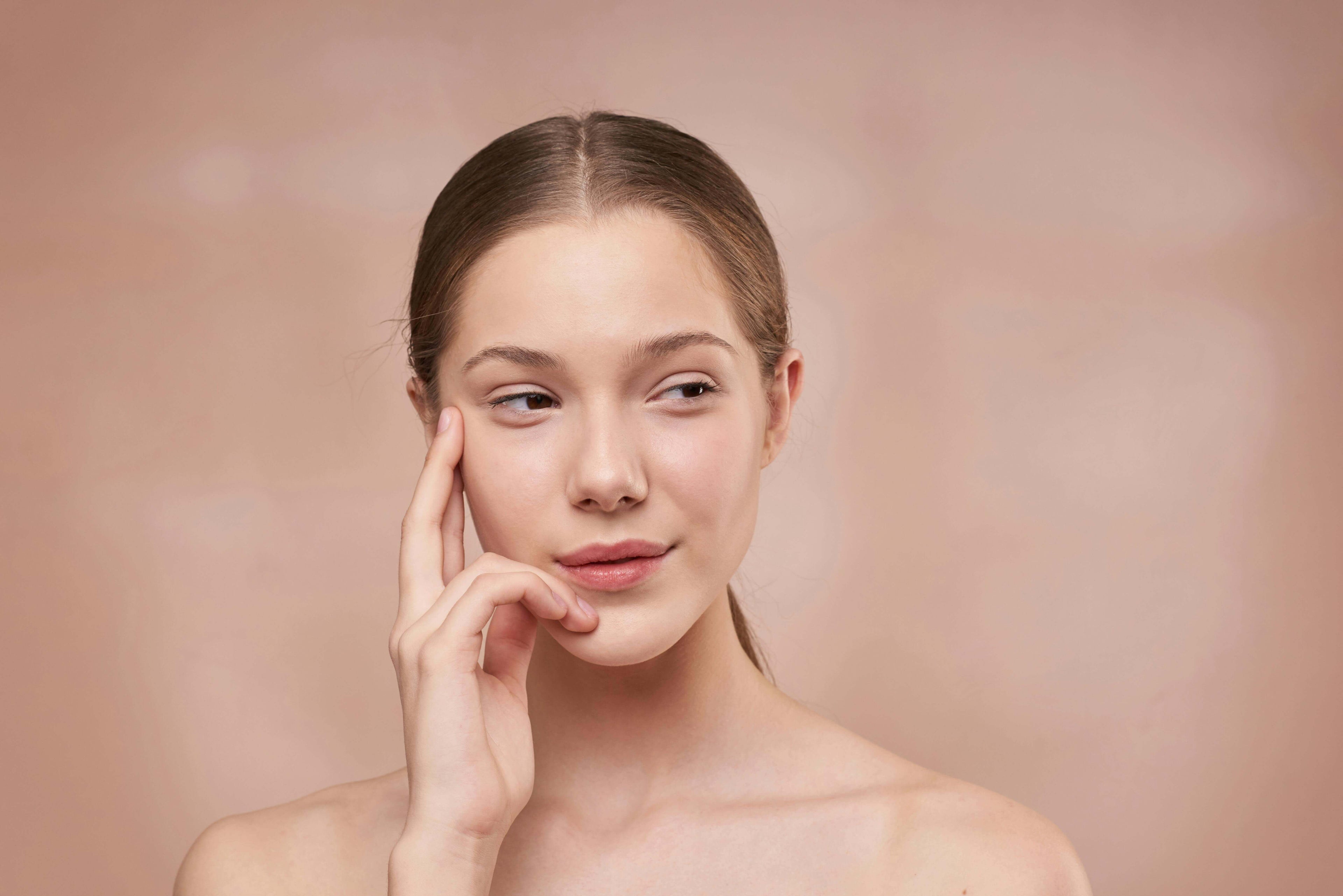 A woman touches her cheek - GaniGlow skin care products for healthy beauty.